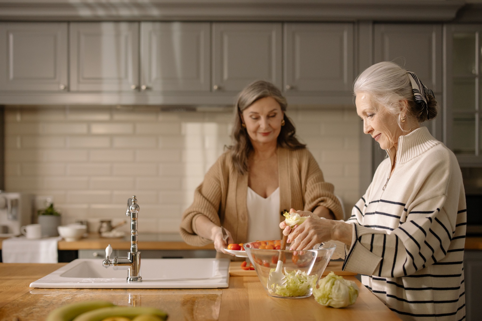 Two women preparing a fresh salad together in the kitchen